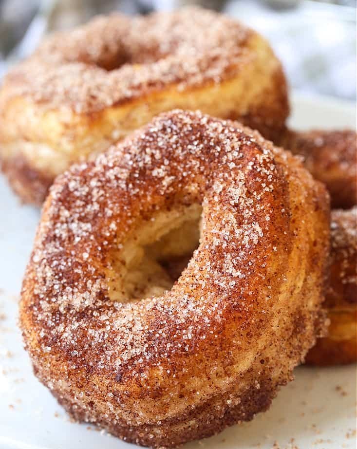 Warm cinnamon sugar air fryer donuts stacked on a serving plate