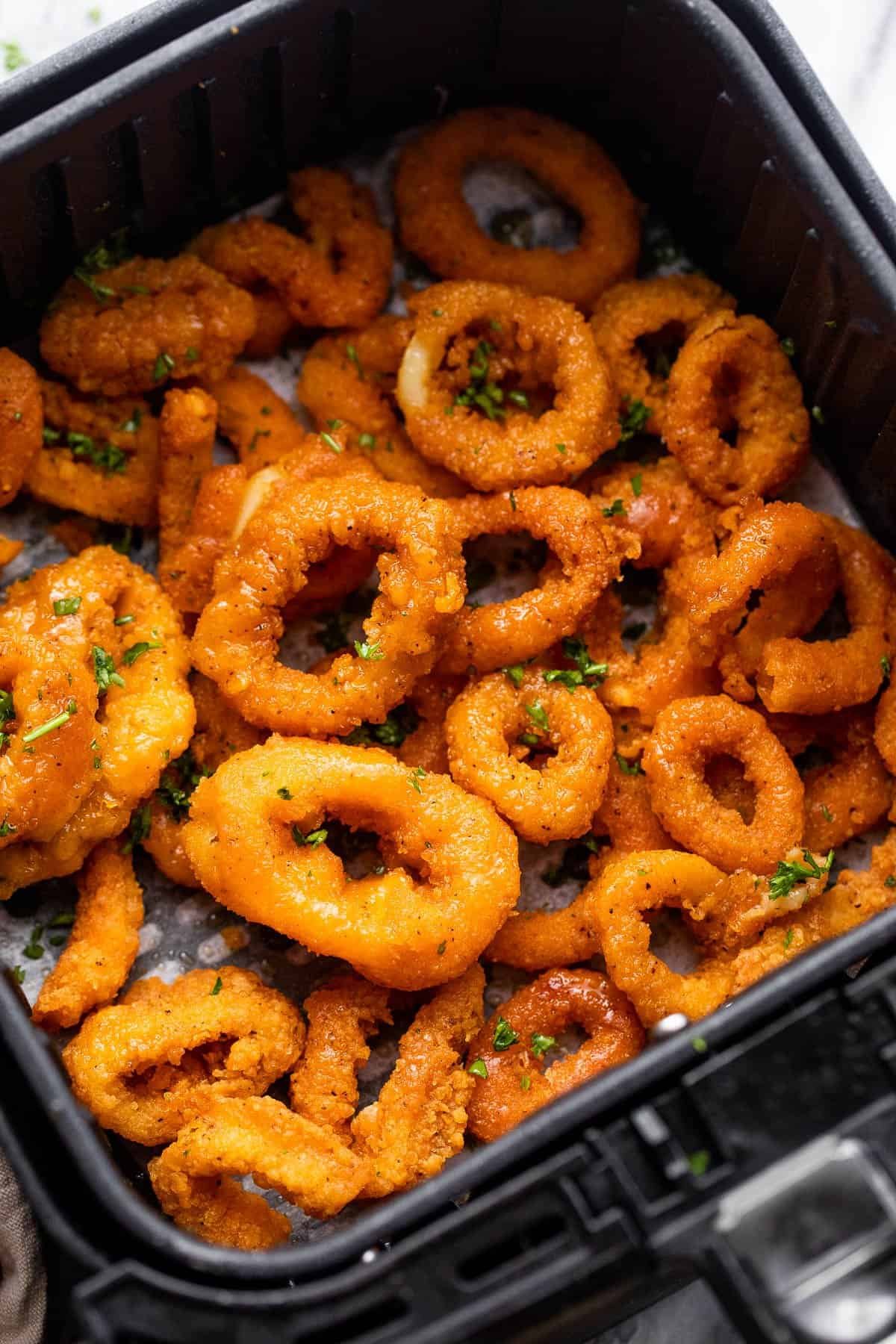 Coated calamari rings arranged in a single layer inside the air fryer