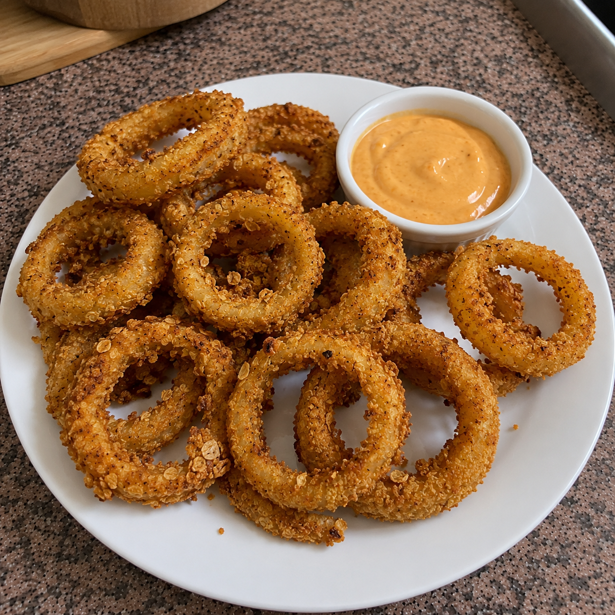 Finished crispy air fryer onion rings on a plate with dipping sauce